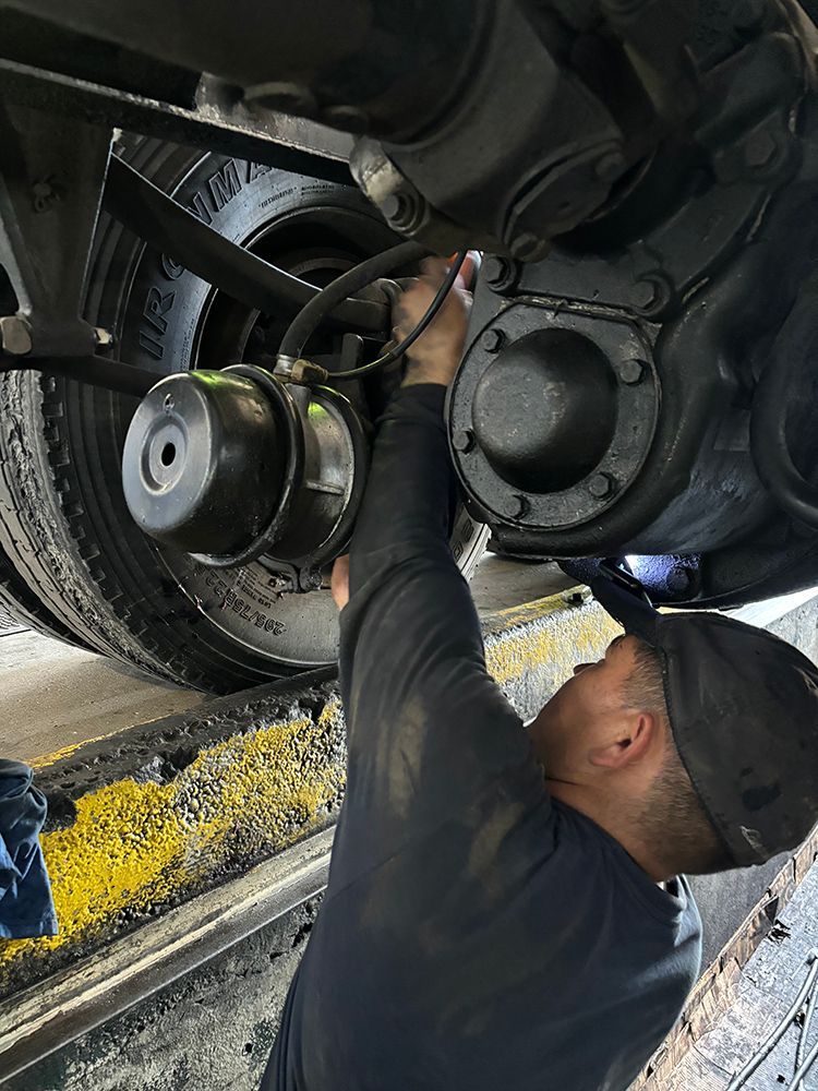 A man is working on the underside of a truck.