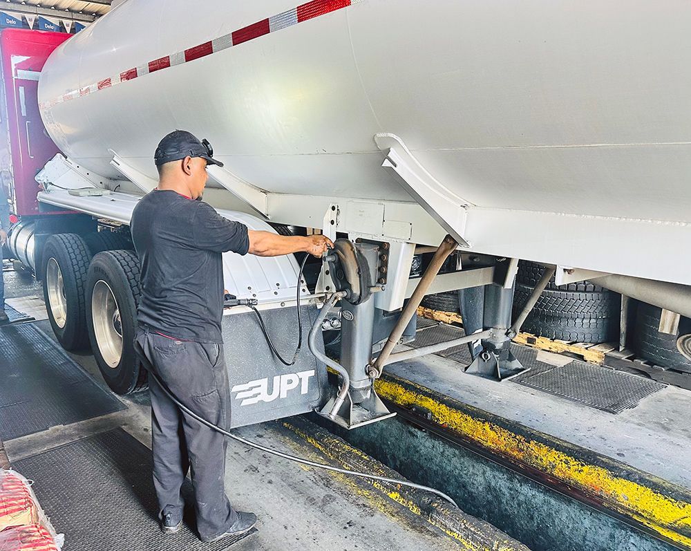 A man is working on a tanker truck in a garage.
