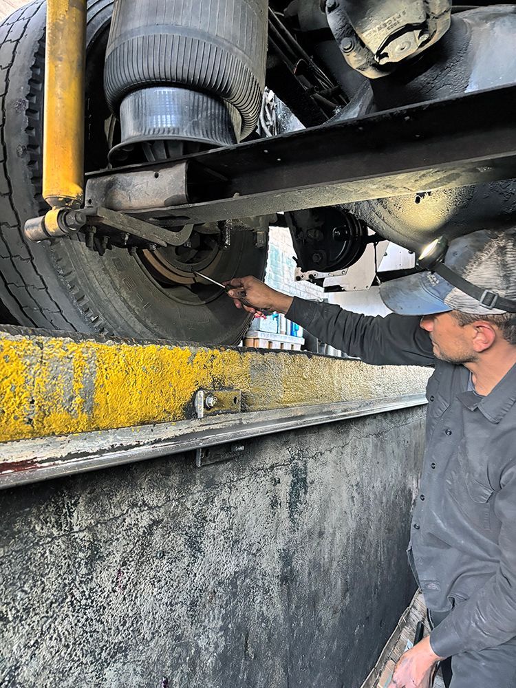 A man is working on the underside of a truck.