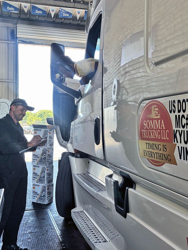A man is standing next to a semi truck in a garage.