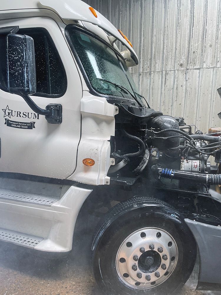 A white truck with its hood open is sitting in a garage.