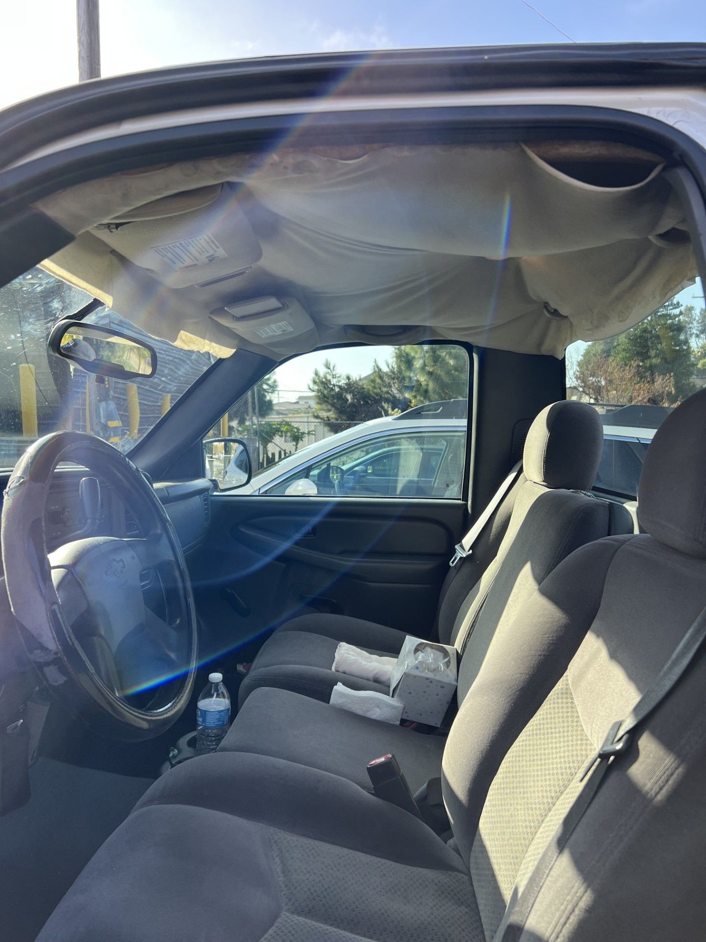 The inside of a truck with a bottle of water in the back seat.