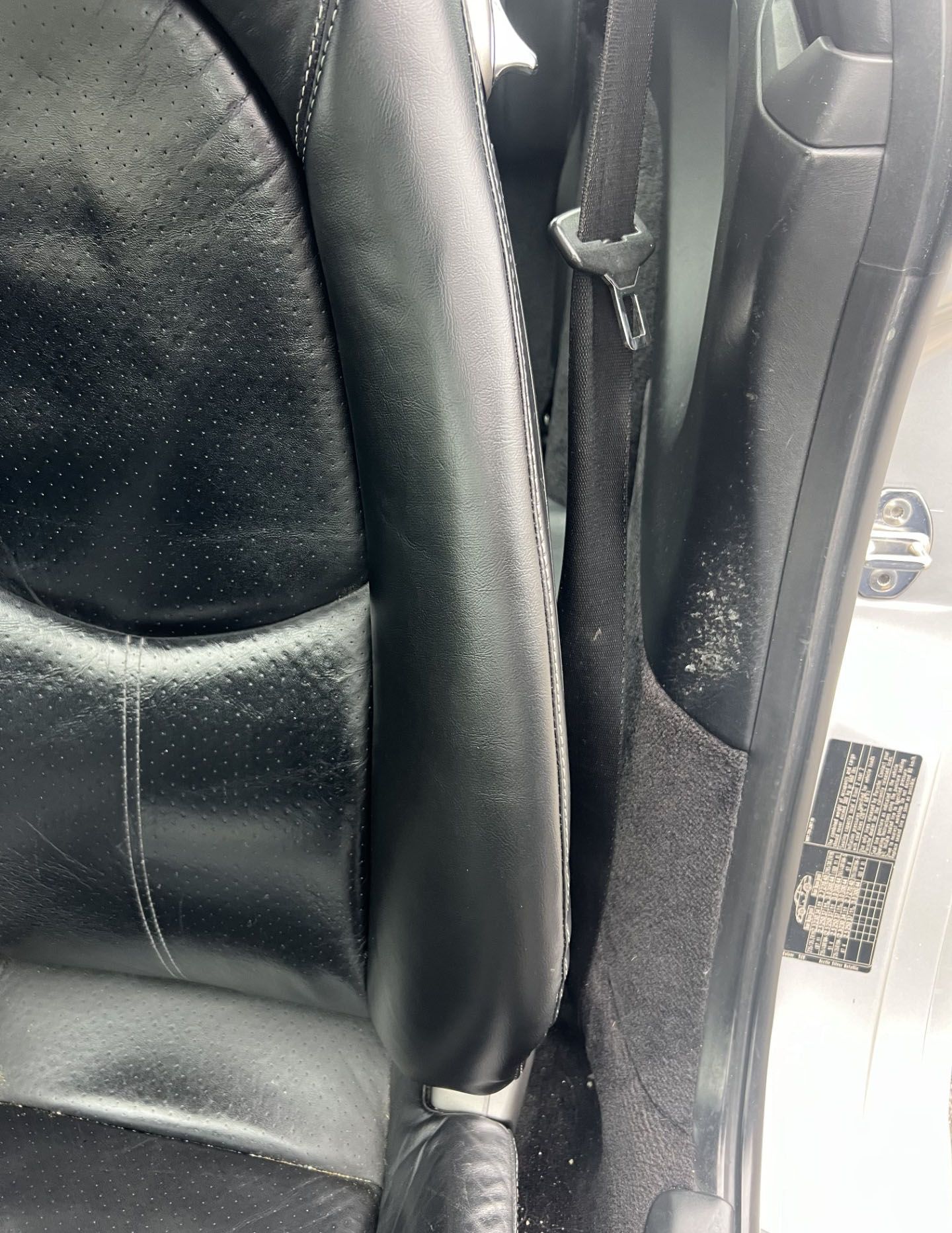 A close up of a black leather seat in a car.