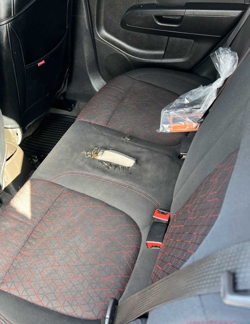 The back seat of a car with a hole in it.