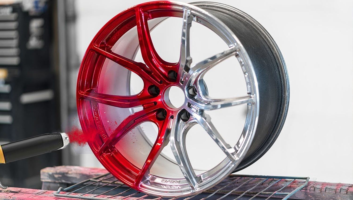 A car wheel is being painted red and silver.