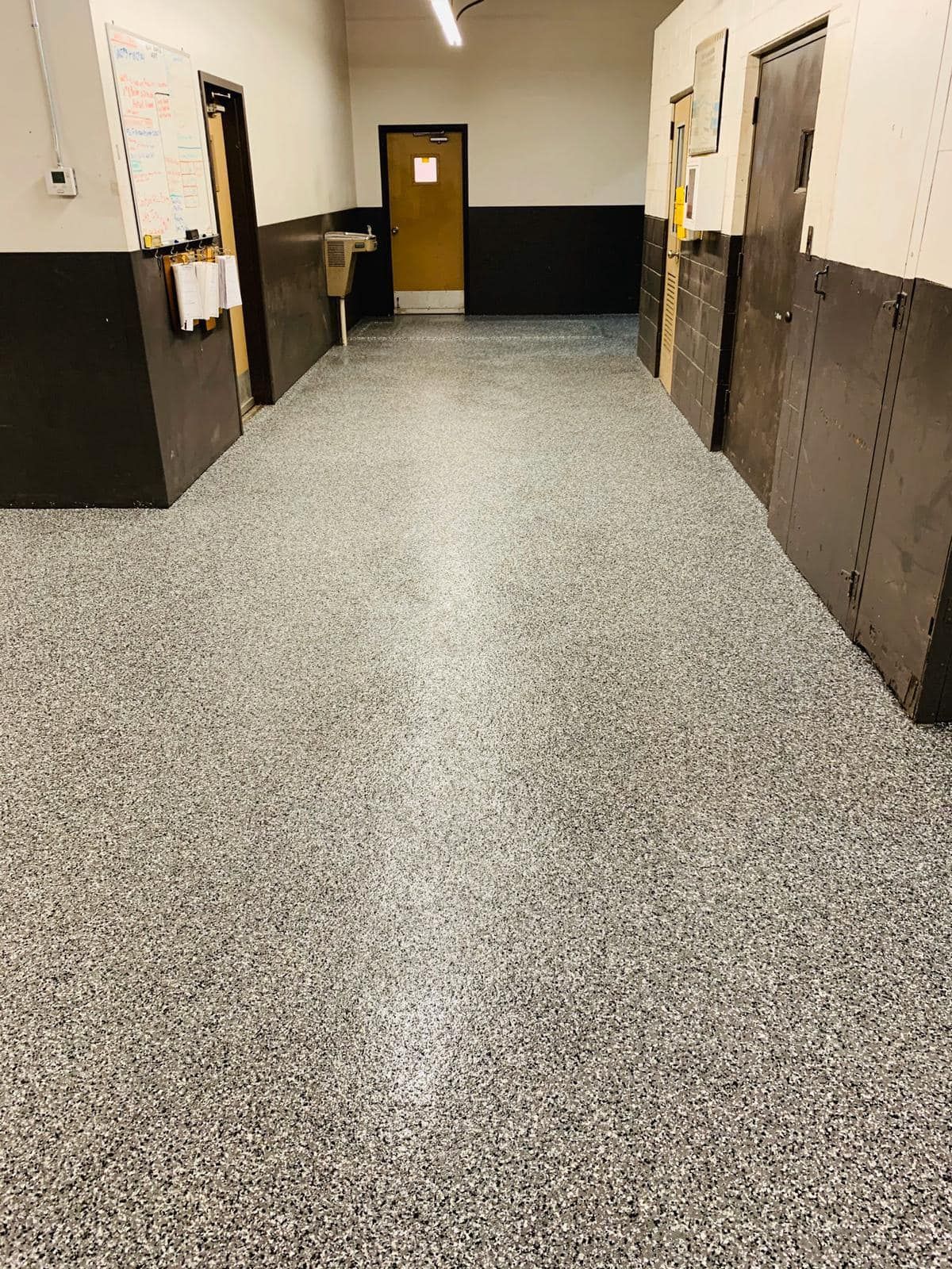 Hallway with speckled gray flooring, dark wainscoting, and closed doors.