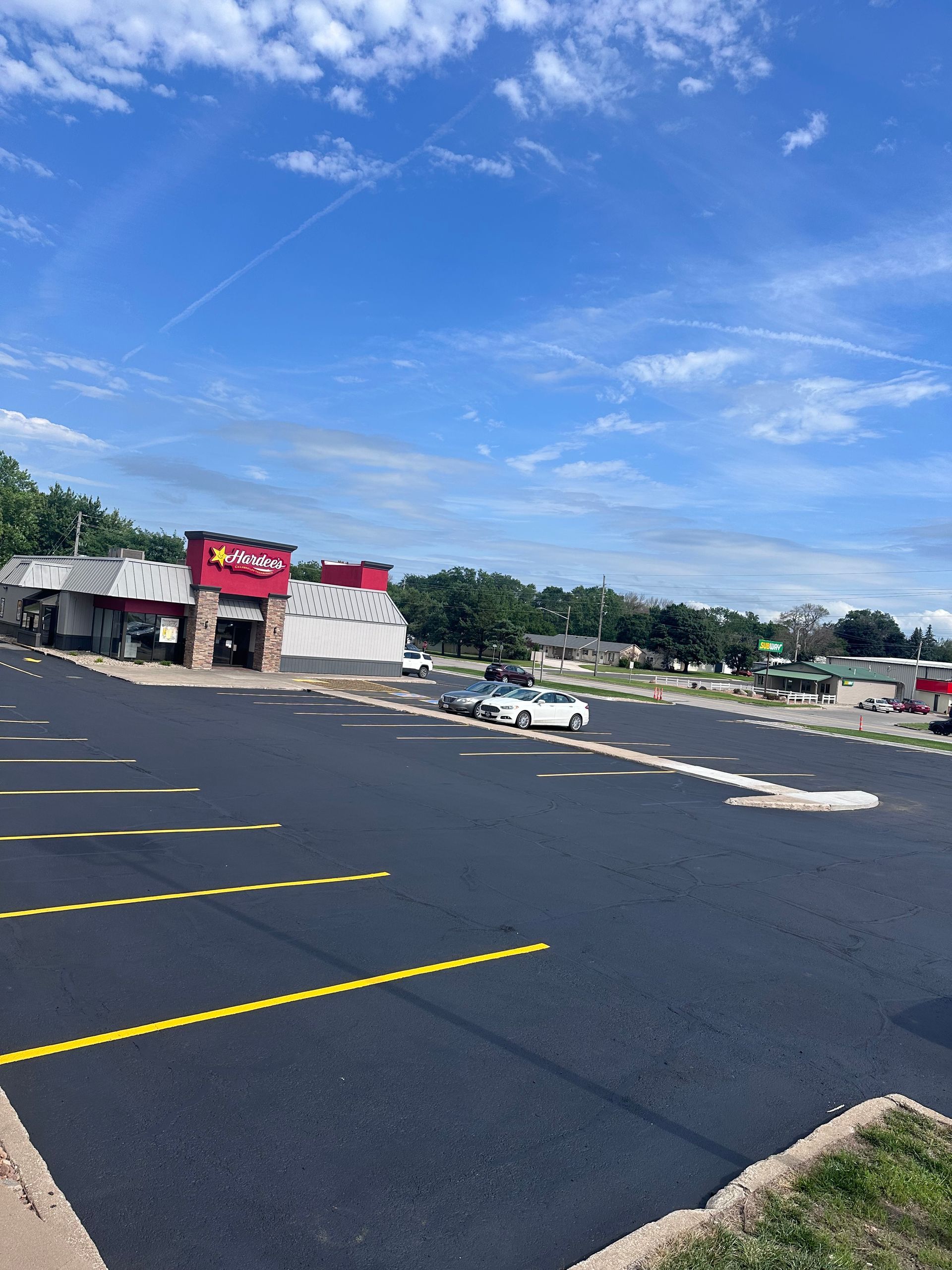 Exterior view of a fast food restaurant, with a paved parking lot and blue sky.
