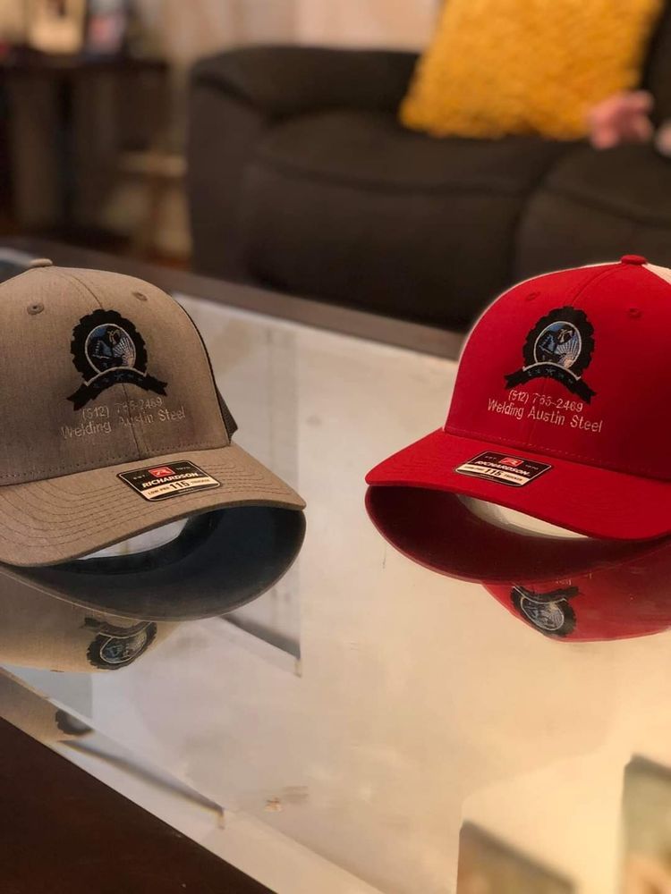 Two baseball caps, one tan and one red, displayed on a glass table in a living room.
