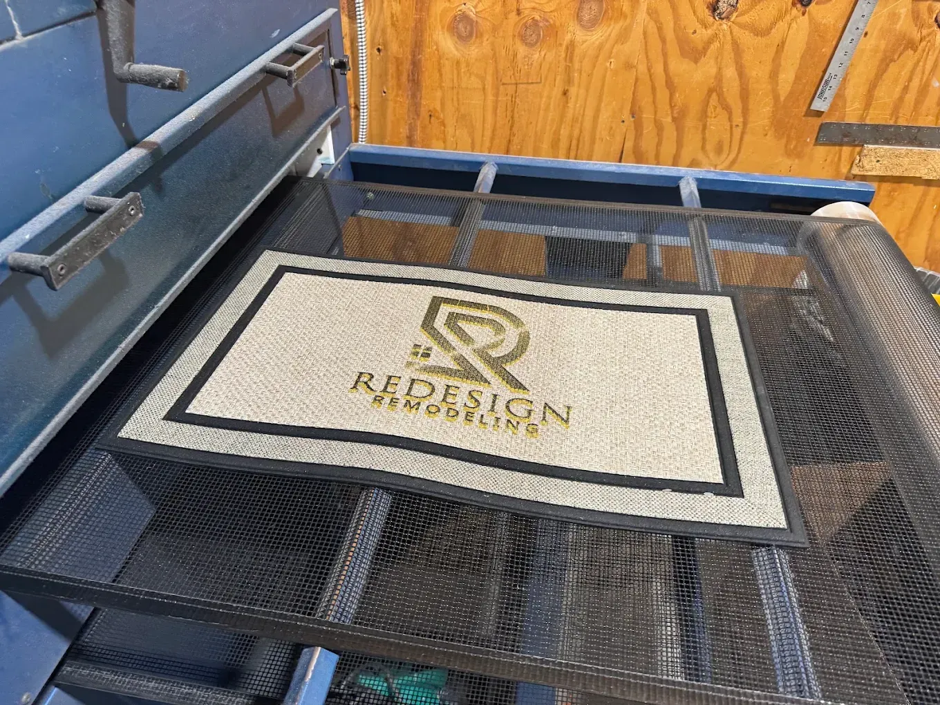 “HUDSON” doormat on a black mesh cart with blue walls and a wooden door in the background