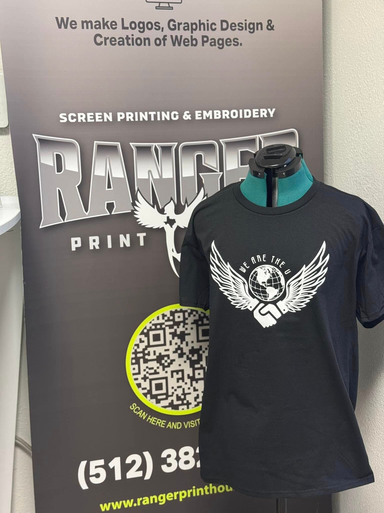 Black T-shirt with white winged graphic displayed on a mannequin in a print shop showroom