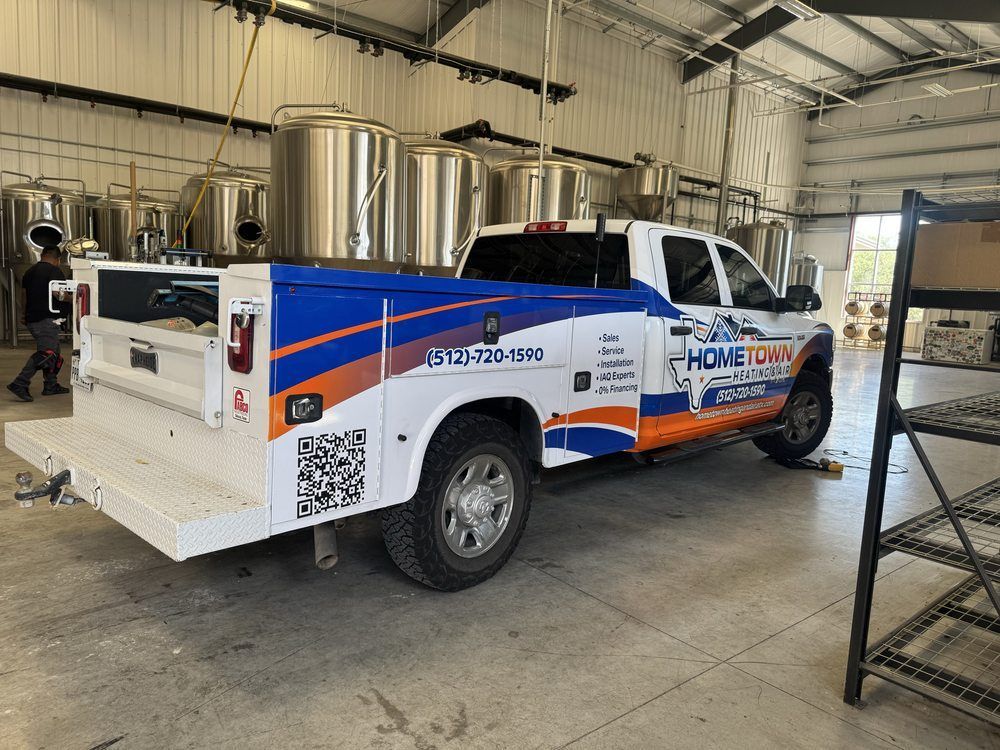 White service truck with blue and orange graphics parked inside an industrial garage.