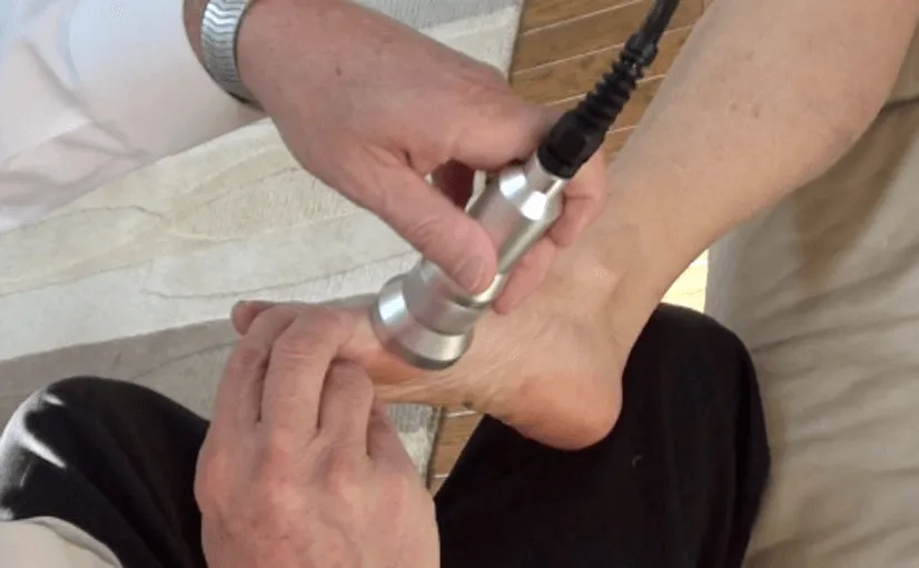 A practitioner uses an ultrasound therapy device on a patient's foot.