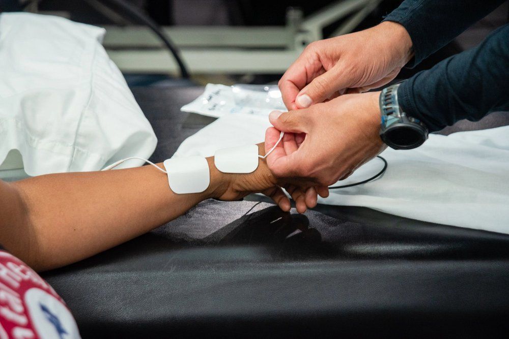A person places adhesive electrodes on a patient's wrist during a medical procedure.