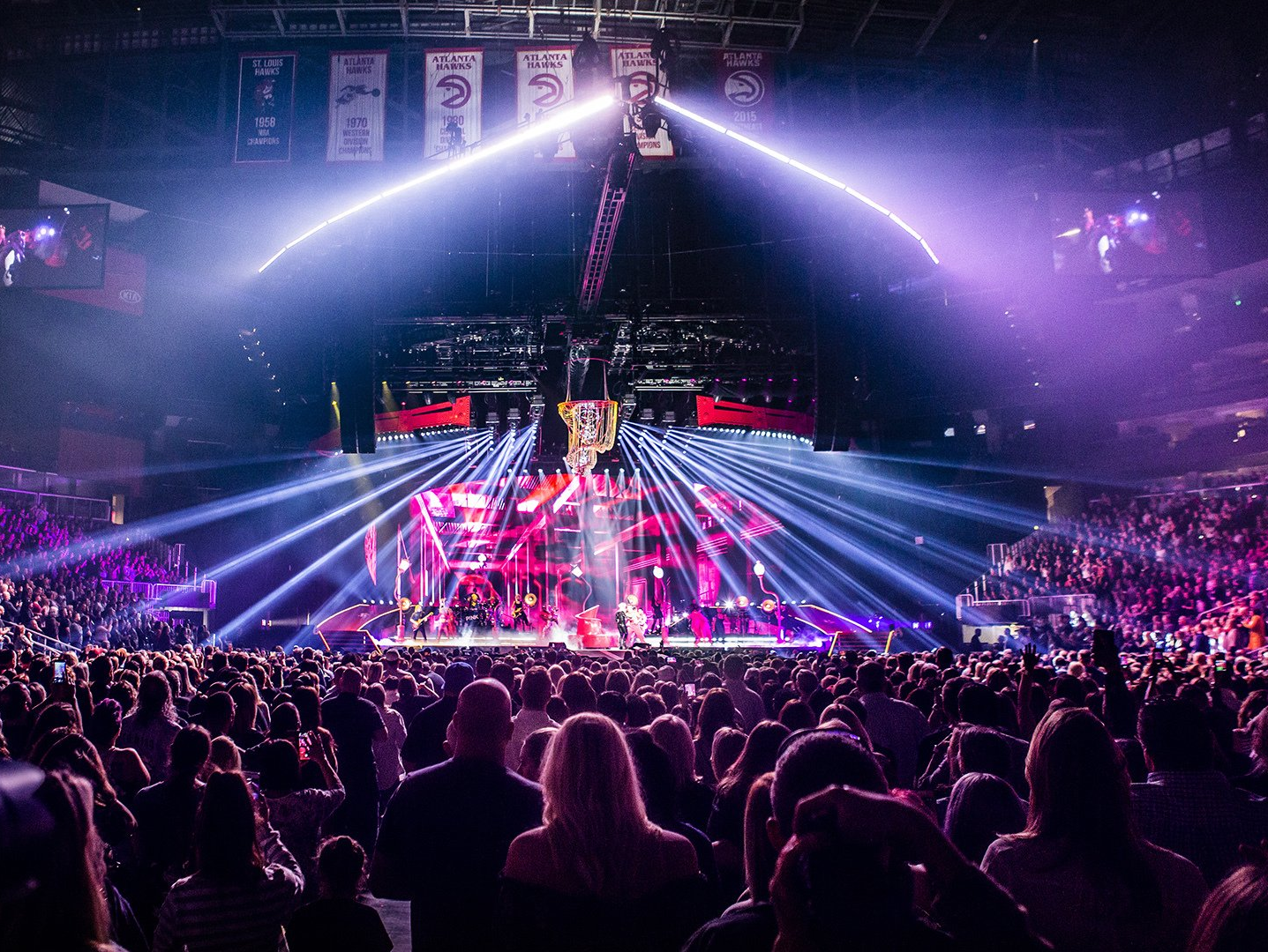 A vibrant live concert scene at an indoor arena, showcasing a packed audience at Allstate Arena