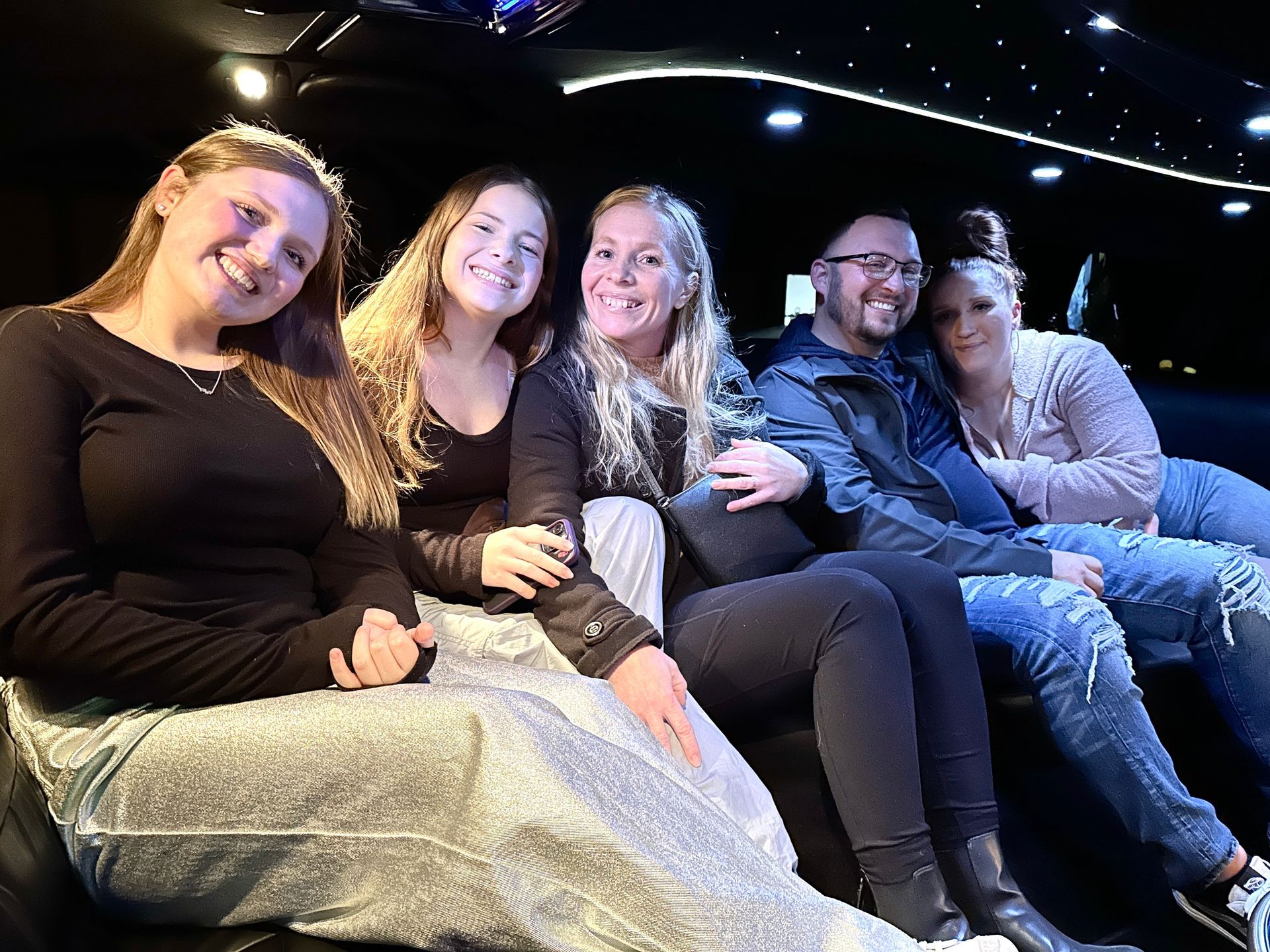 A cheerful group of five adults is comfortably seated inside Rockford Rides luxurious limousine