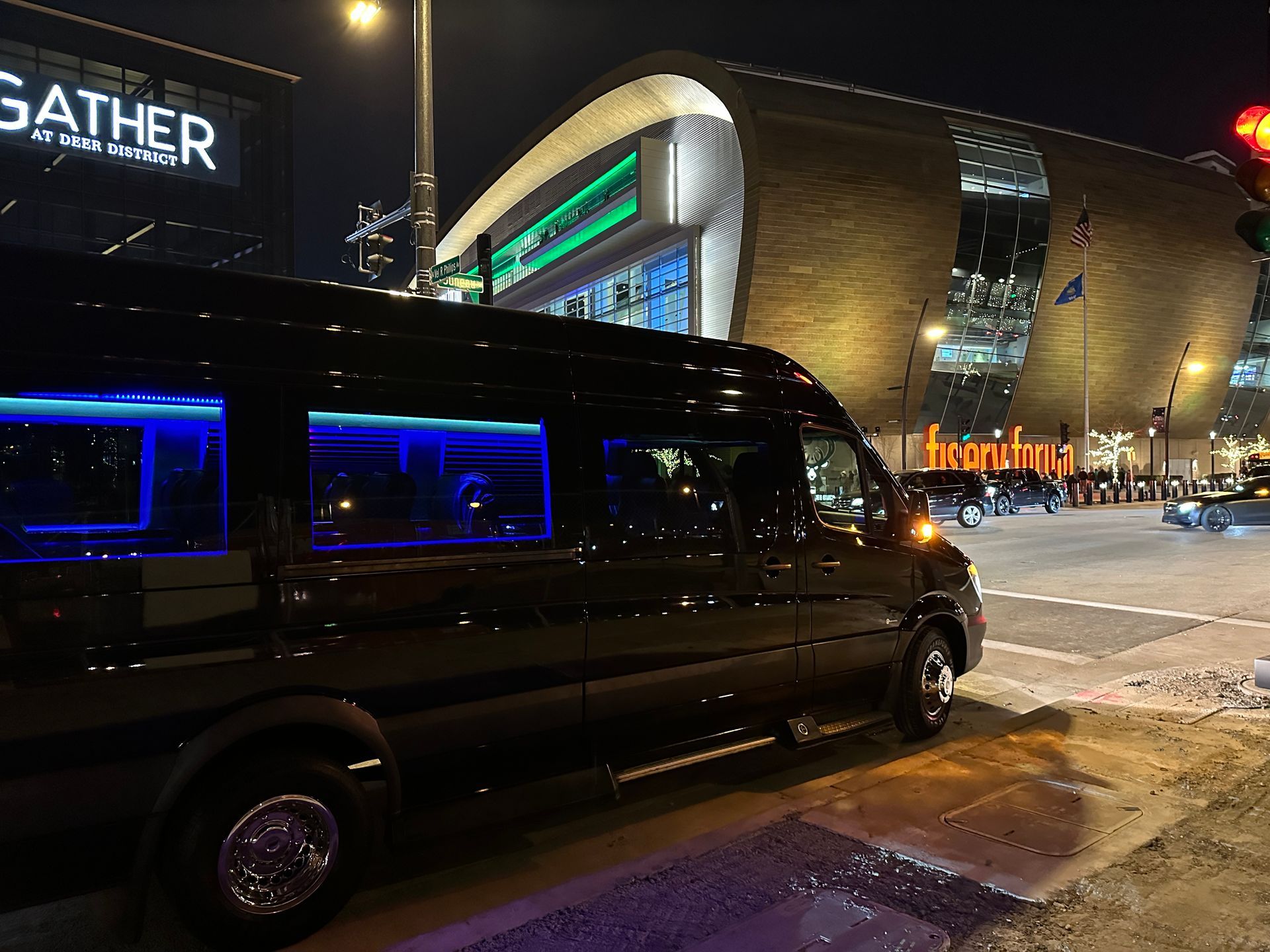 A sleek Rockford Rides limousine parked outside Fiserv Forum at night, its interior aglow 