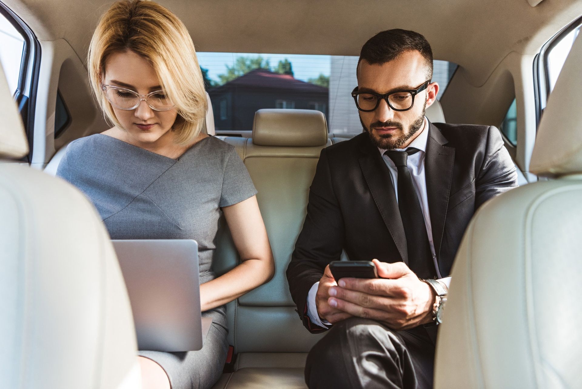 handsome businessman and assistant working in rockford rides limousine with laptop and smartphone 