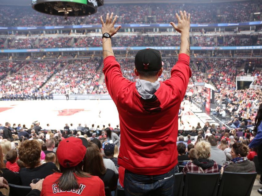 A group of professionally dressed individuals stands confidently in front of a sleek black party bus on a city street, likely in Chicago, Illinois. They exhibit a mix of stylish business and smart casual attire, ready for an event. The image suggests the group is using Rockford Rides Limo service for comfortable and stylish group transportation, enhancing their city experience with the convenience and luxury of a party bus.