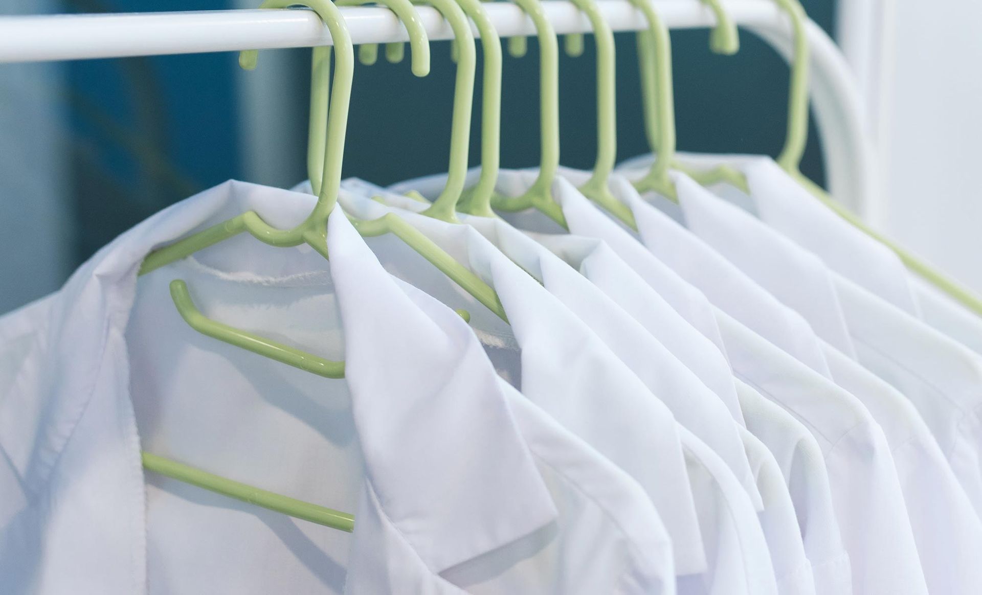 A row of white lab coats hanging on a rack.
