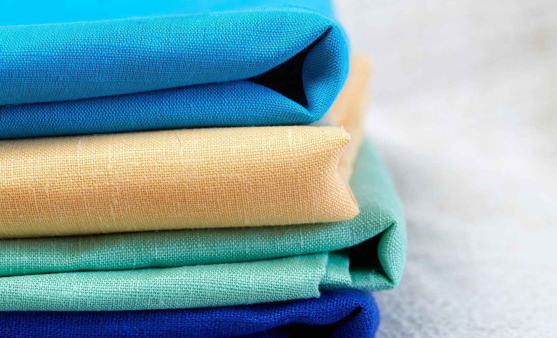 A close up of a stack of different colored fabrics.