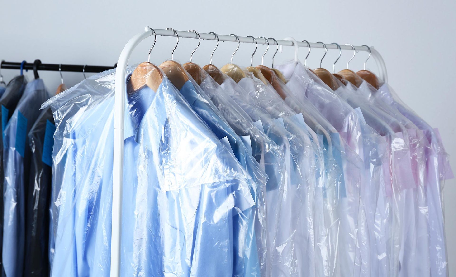 The shirts are wrapped in plastic and hanging on a rack.