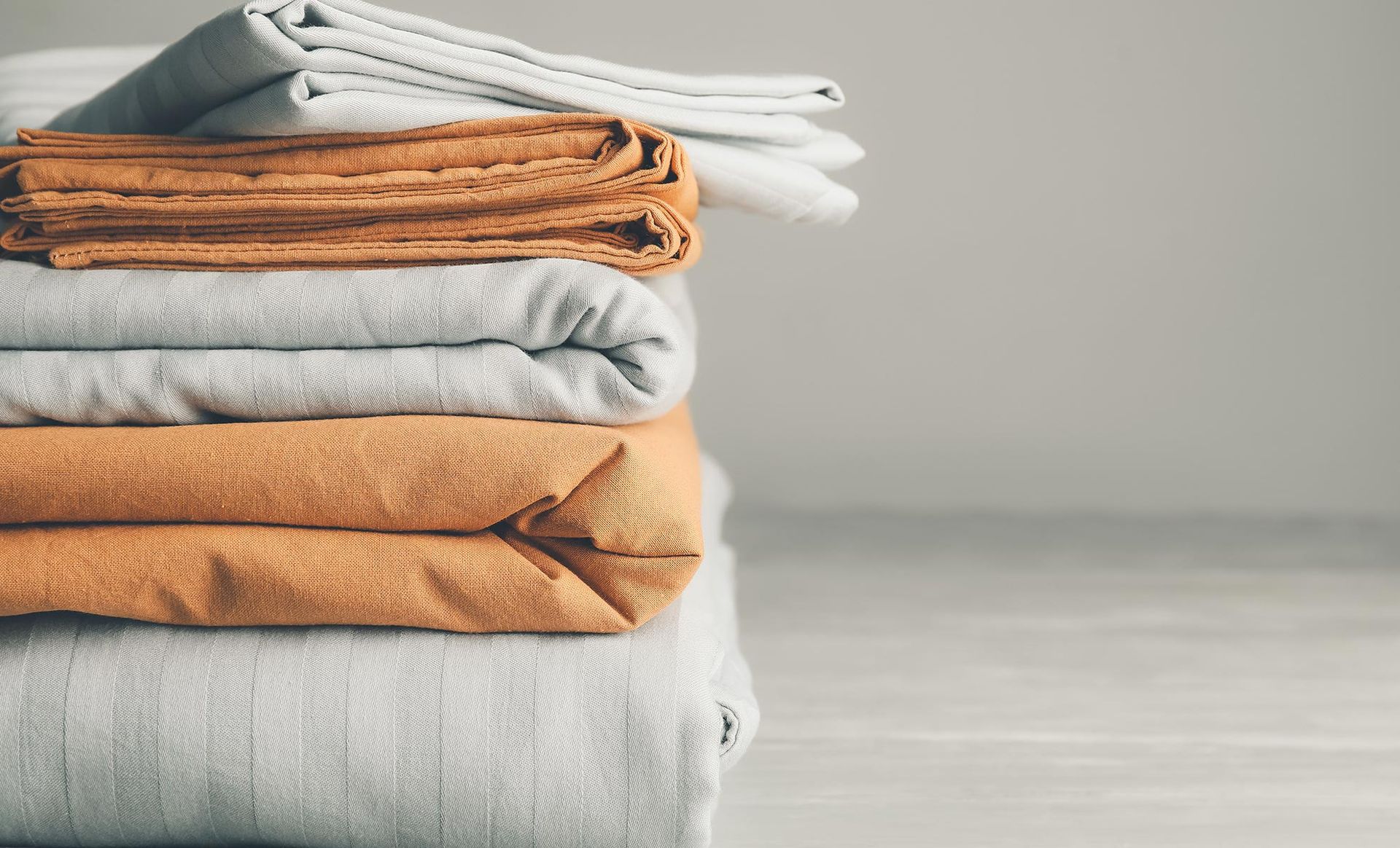 A pile of sheets and towels stacked on top of each other on a table.