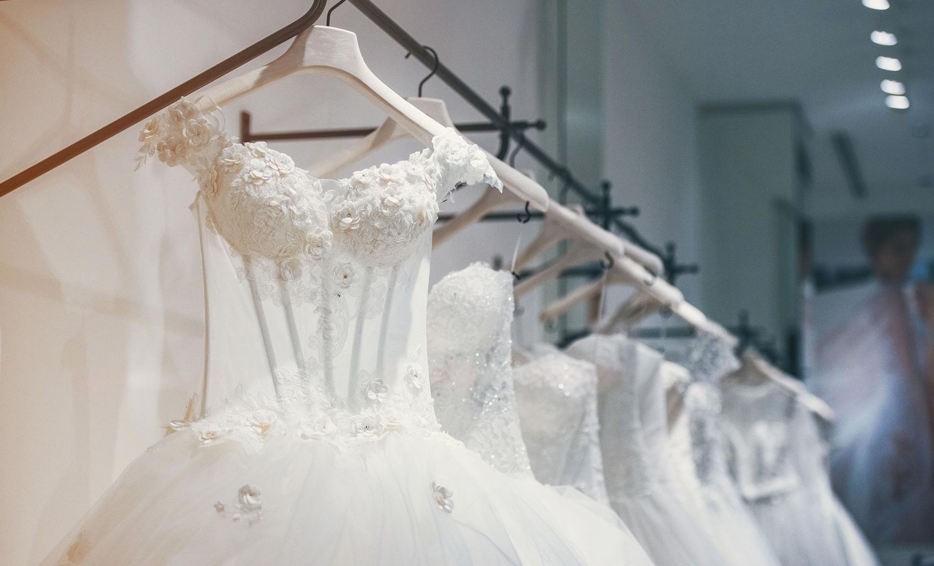 A row of wedding dresses hanging on a rack in a store.