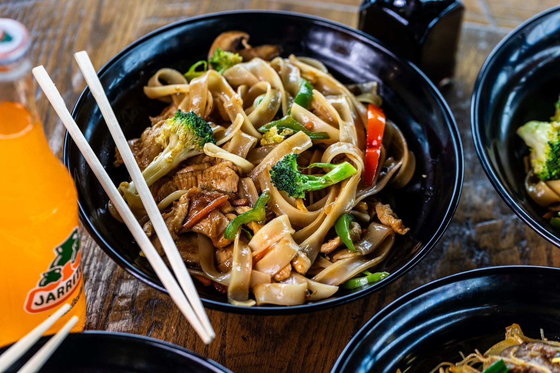Bowl of salad with chicken, oranges, and cilantro. Jarritos soda in the background.