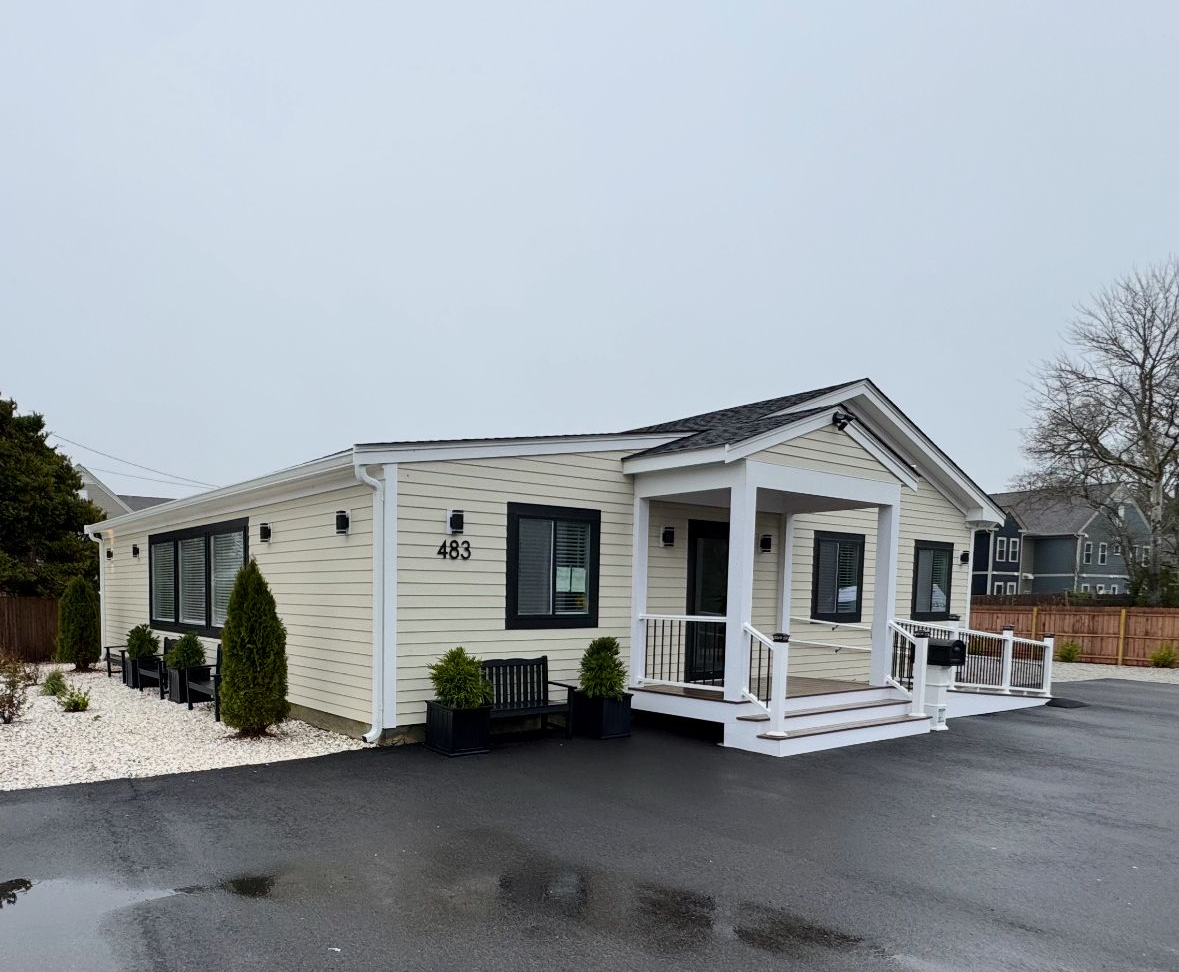 Two-story house with grey siding, white trim, green front door, and multiple windows.