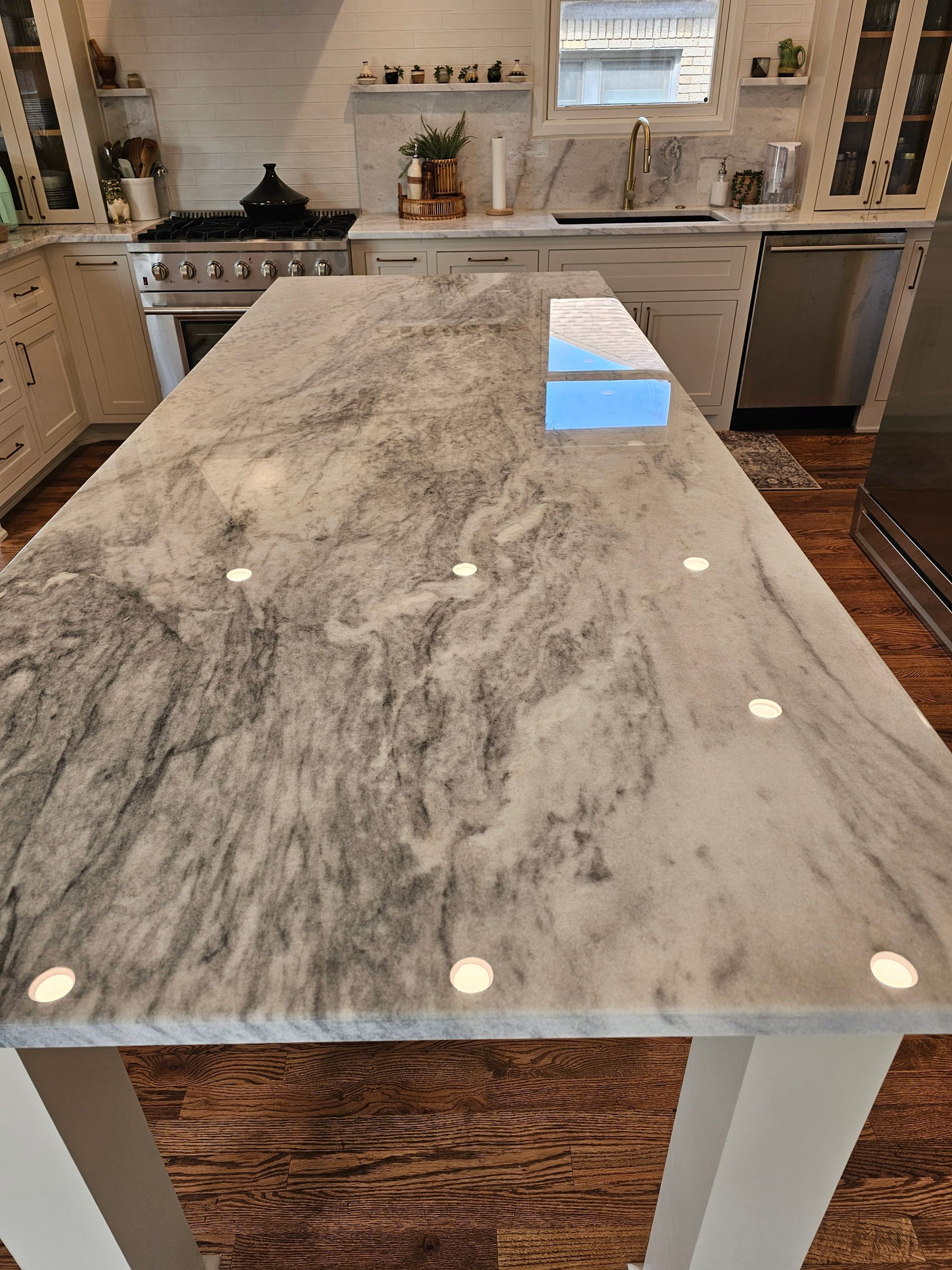 Kitchen with a marble countertop island and white cabinets.