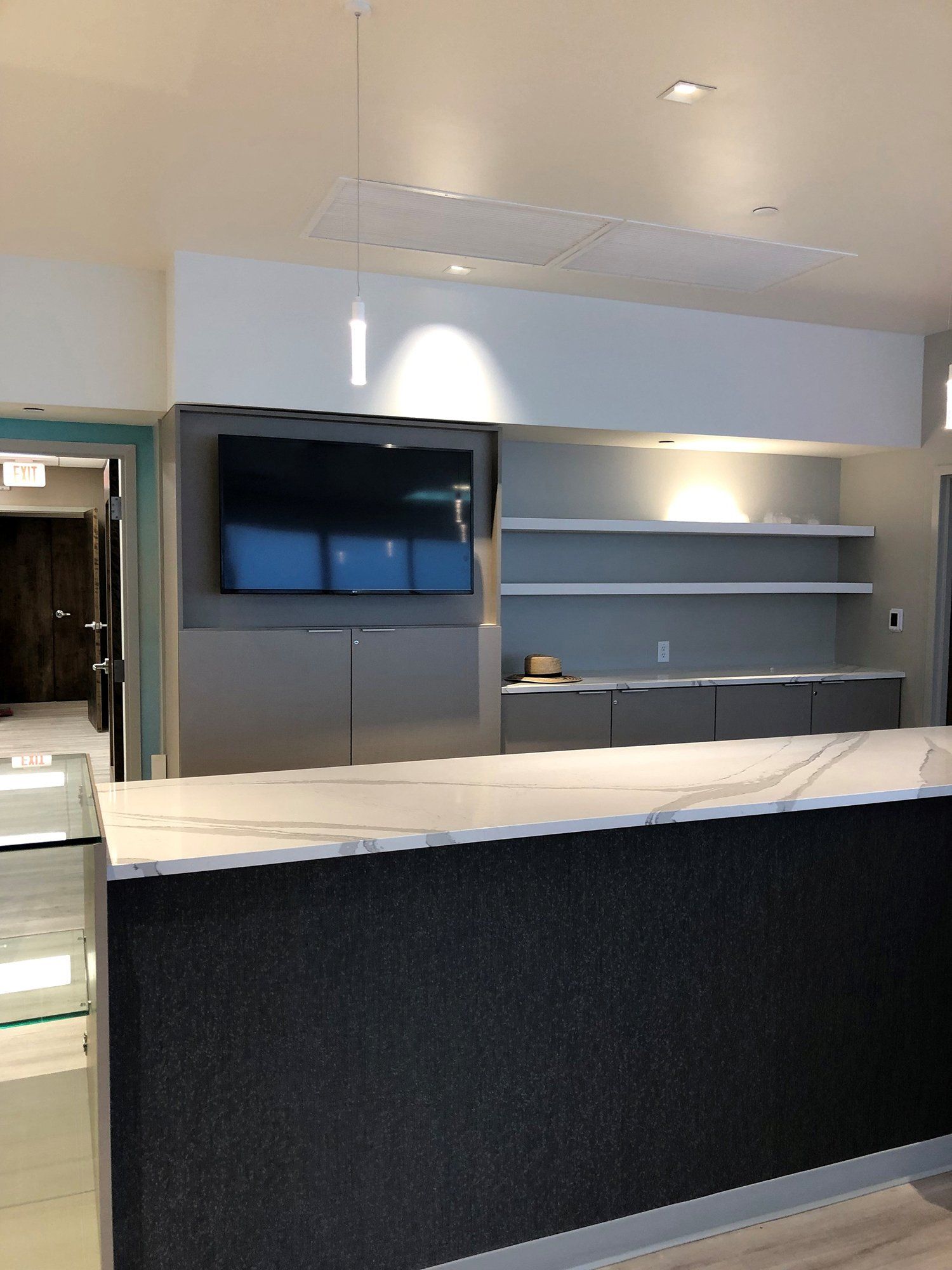 A kitchen with a marble counter top and a flat screen tv on the wall