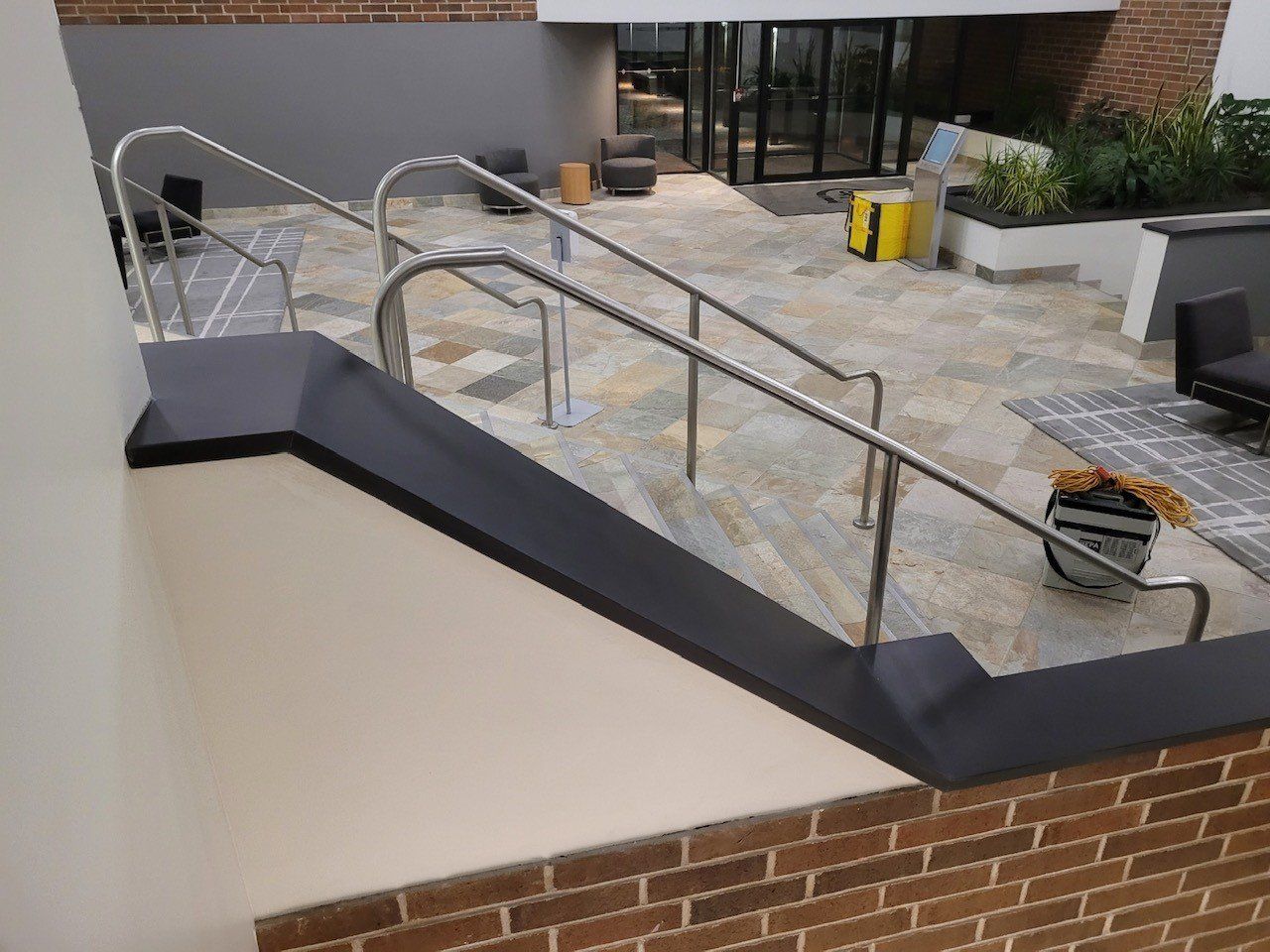 A staircase with a stainless steel railing and a brick wall