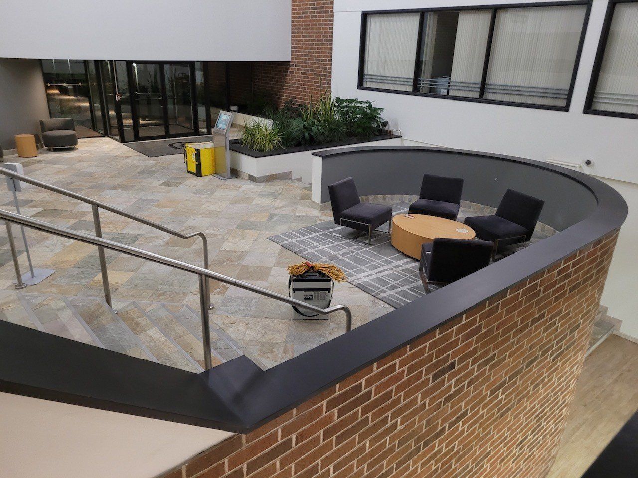 A brick wall surrounds a patio area with chairs and tables