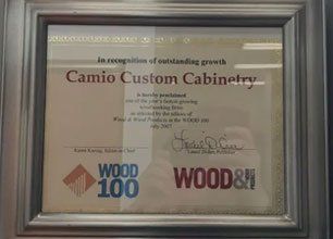 A framed certificate for camio custom cabinetry is hanging on a wall.