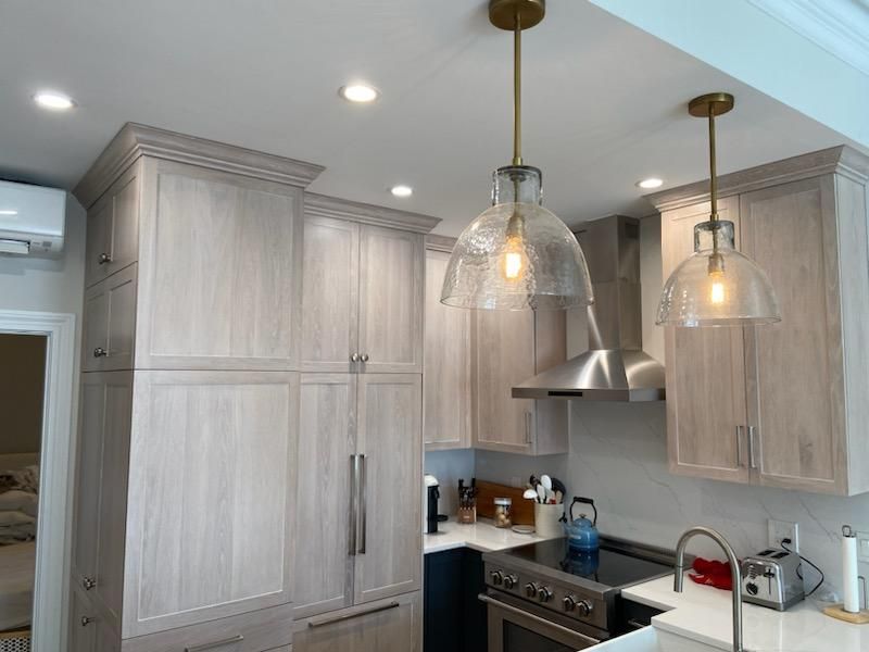 A kitchen with white cabinets and stainless steel appliances and two pendant lights hanging from the ceiling.