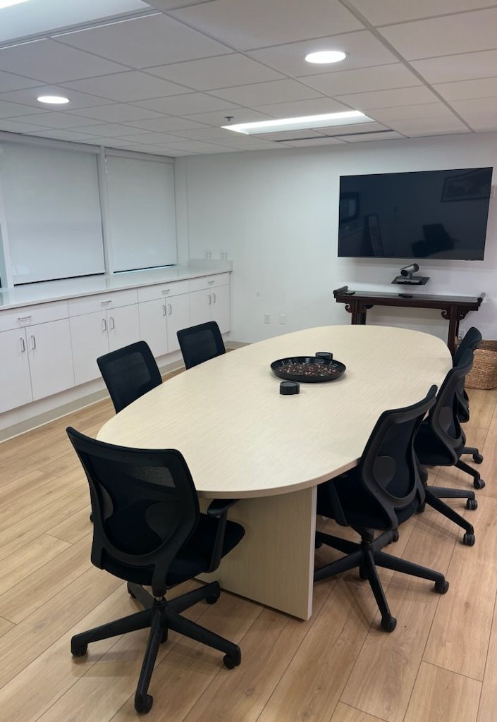 A conference room with a long table and chairs and a flat screen tv.