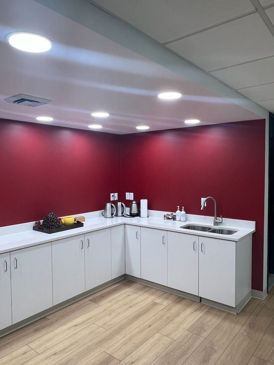 A kitchen with red walls and white cabinets and a sink