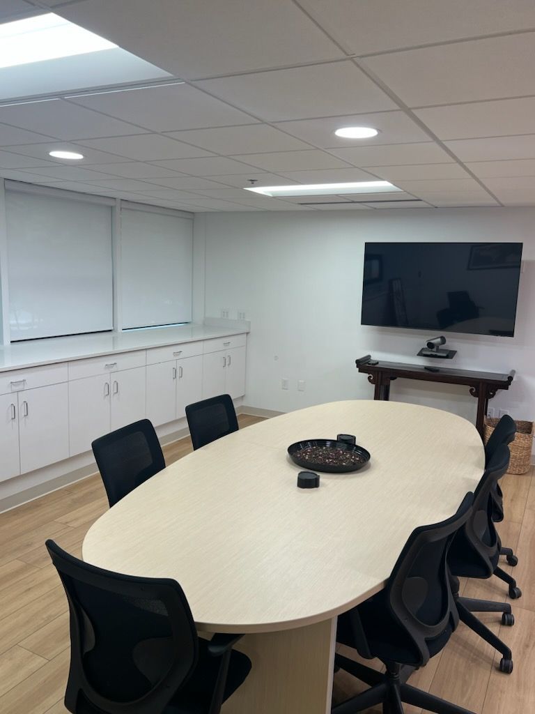 A conference room with a long table and chairs and a flat screen tv on the wall.
