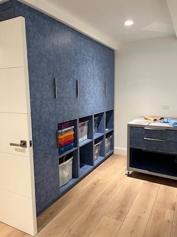 A room with blue cabinets and shelves and a white door.
