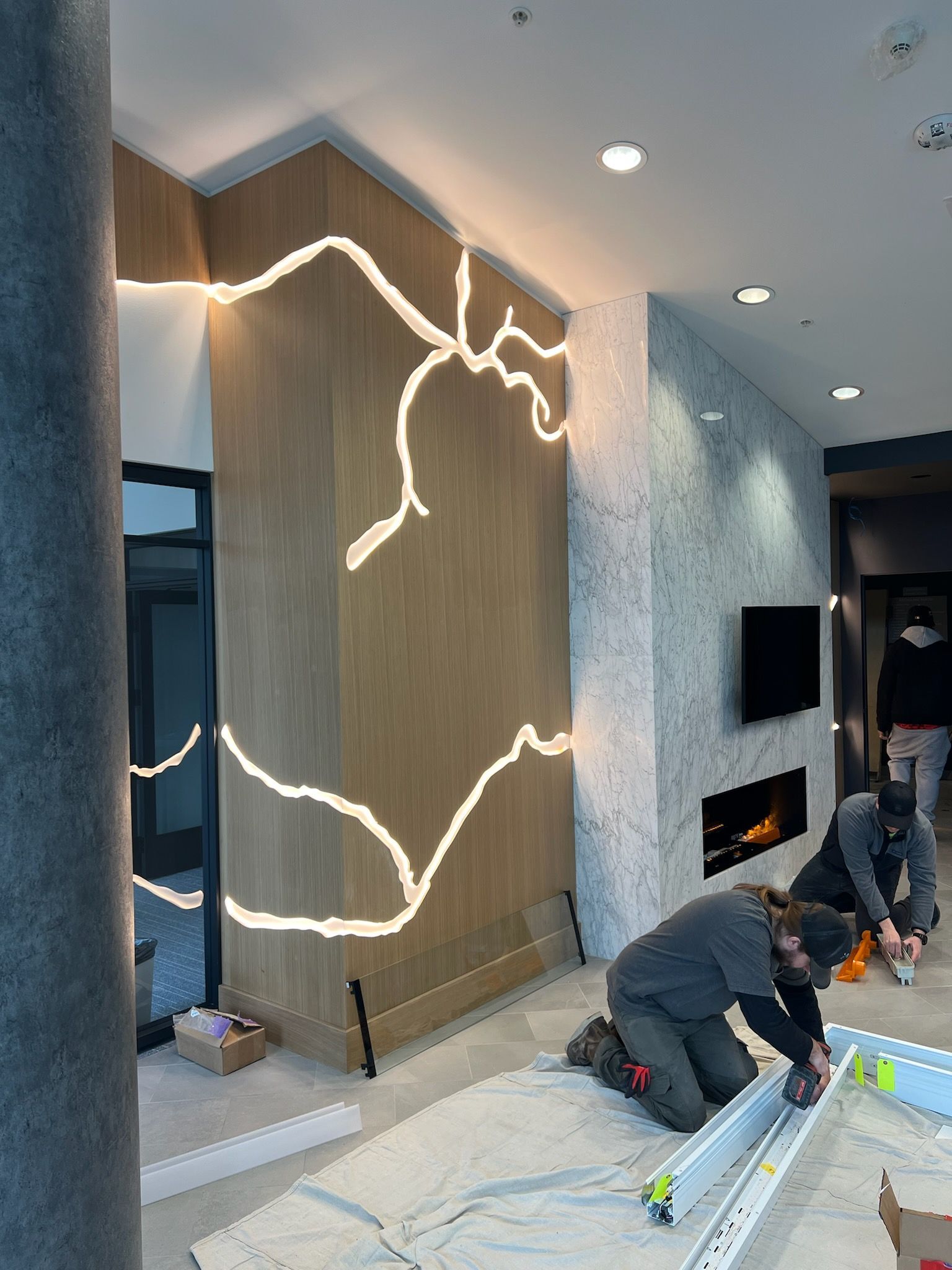 A group of men are working on a fireplace in a living room.