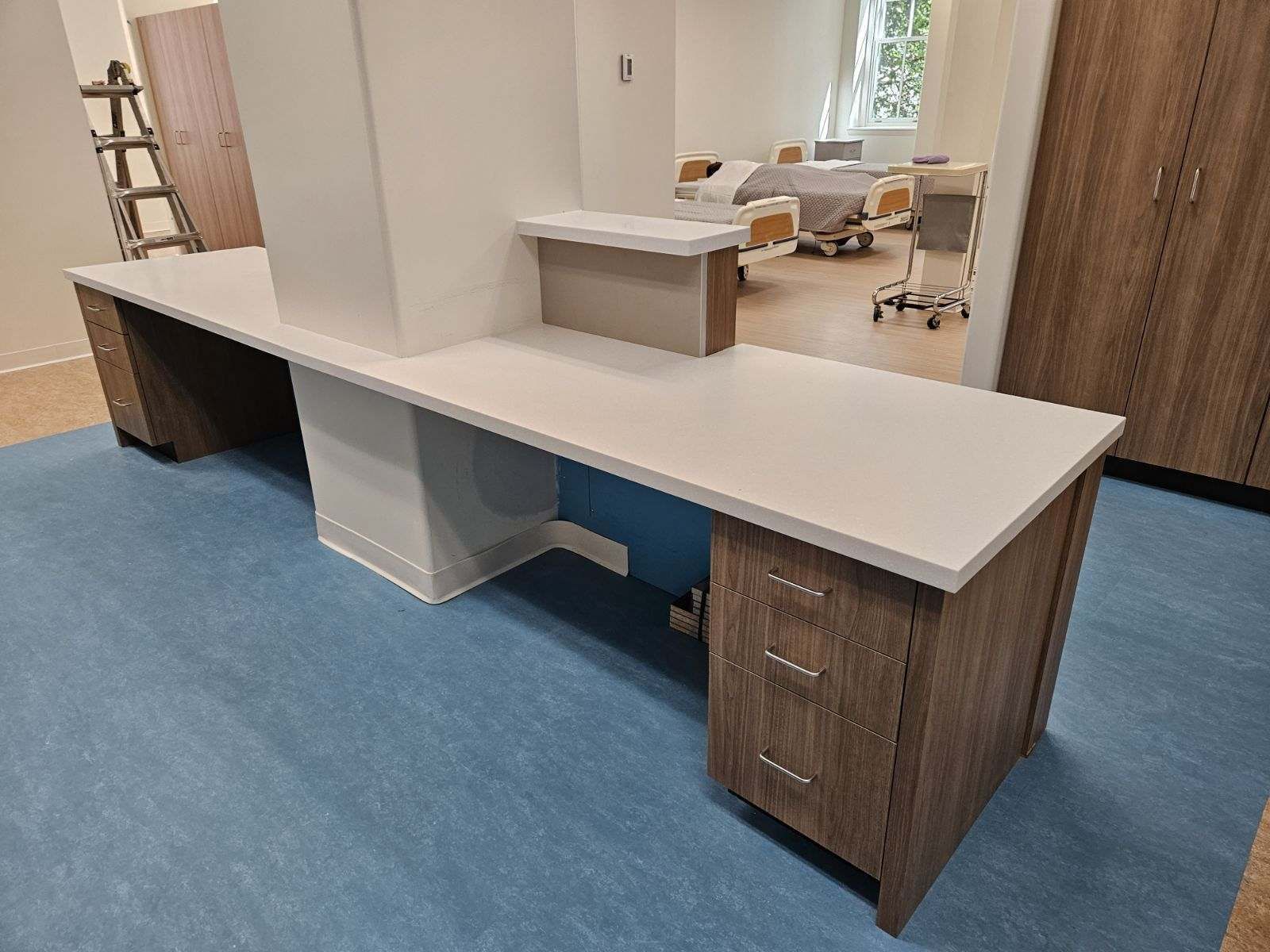 A long desk in a hospital room with a ladder in the background.