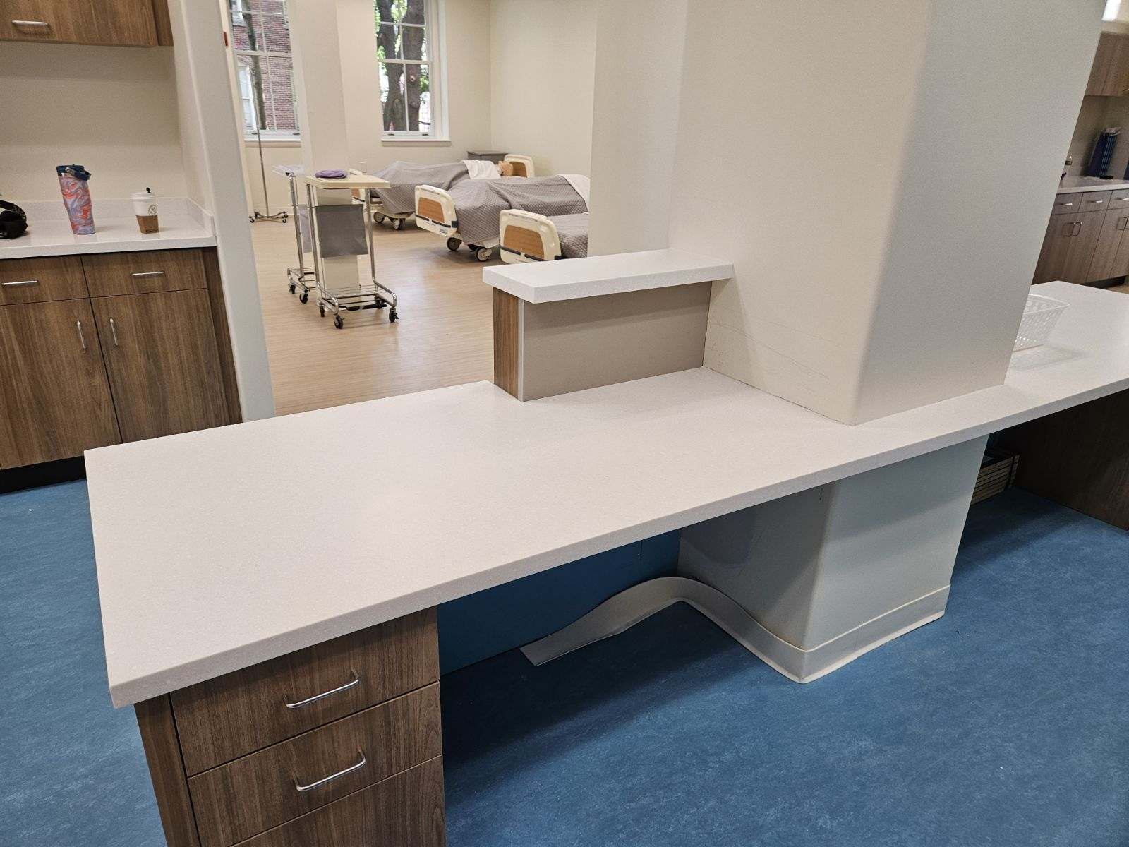 A hospital room with a long desk and a row of beds.