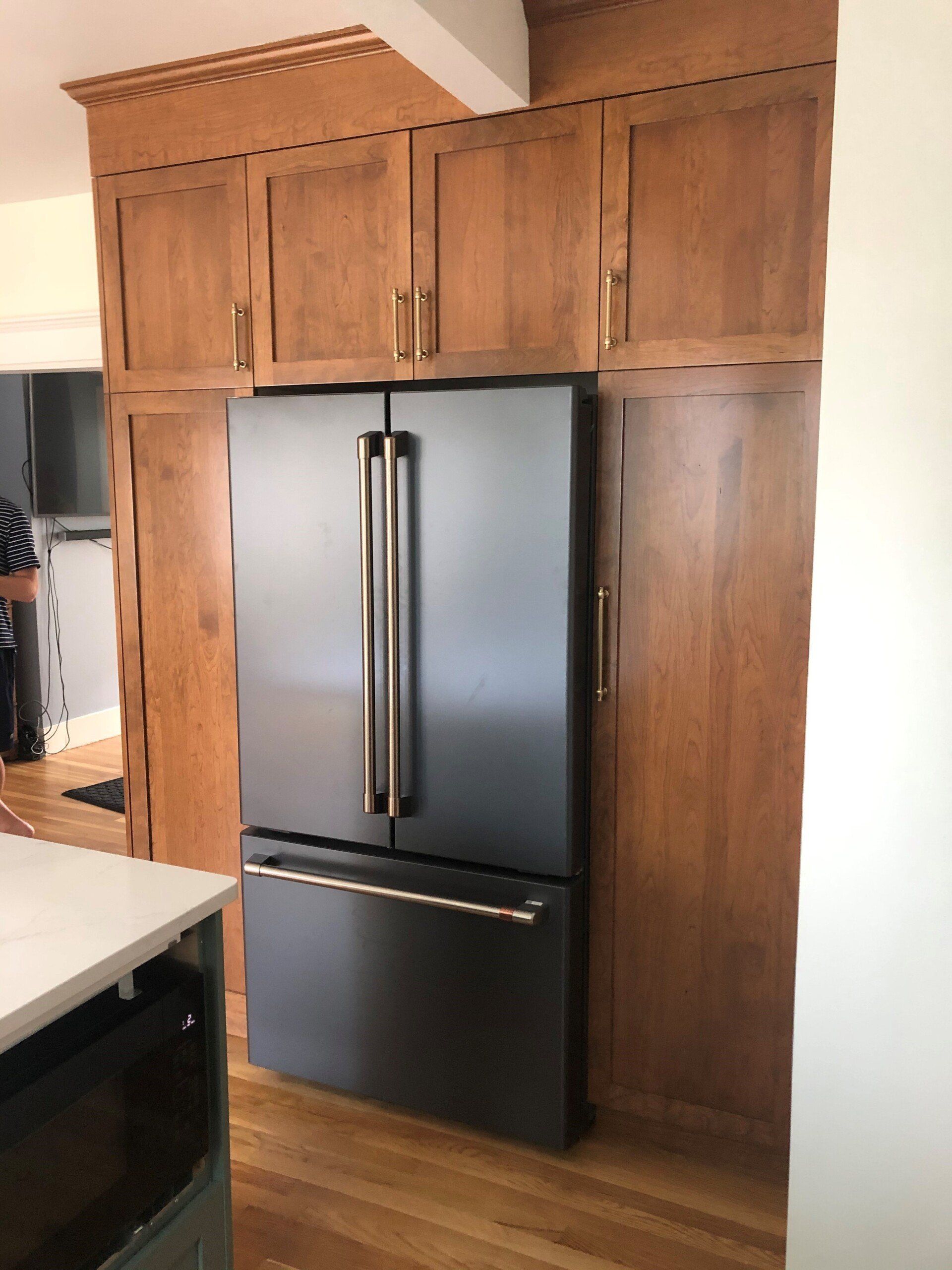A black refrigerator in a kitchen with wooden cabinets