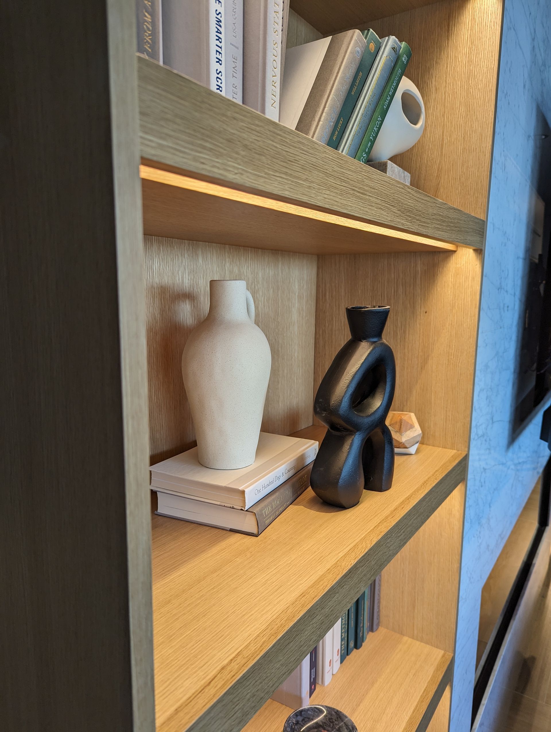 A bookshelf with a vase and a sculpture on it