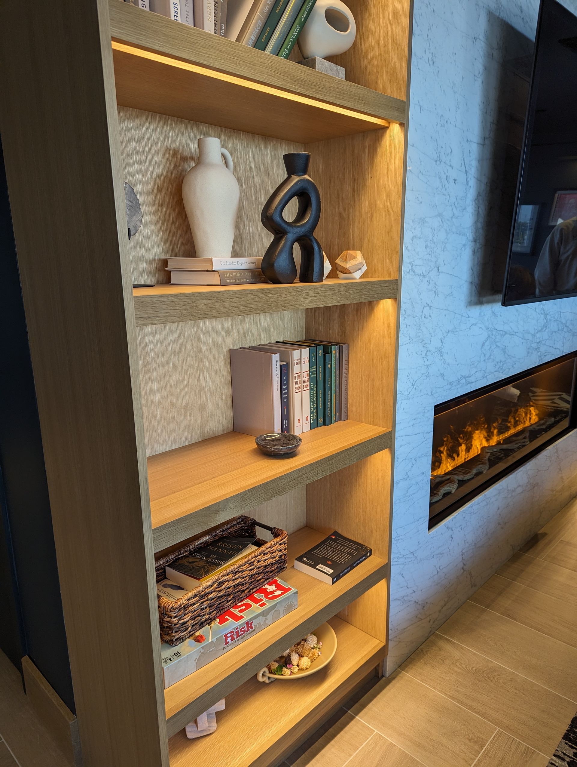 A bookshelf with books and vases on it in a living room.
