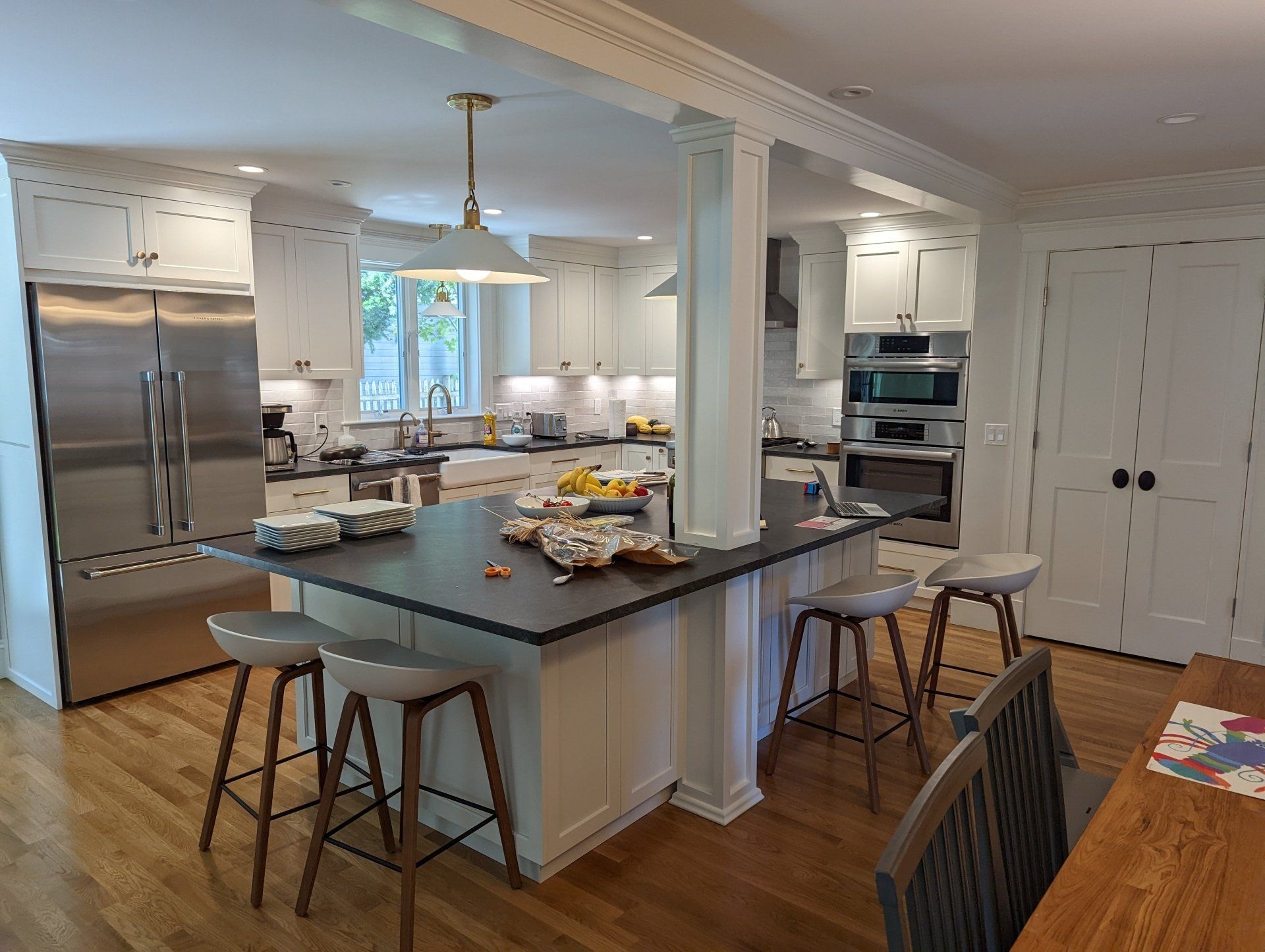 A kitchen with white cabinets and stainless steel appliances and a large island in the middle.