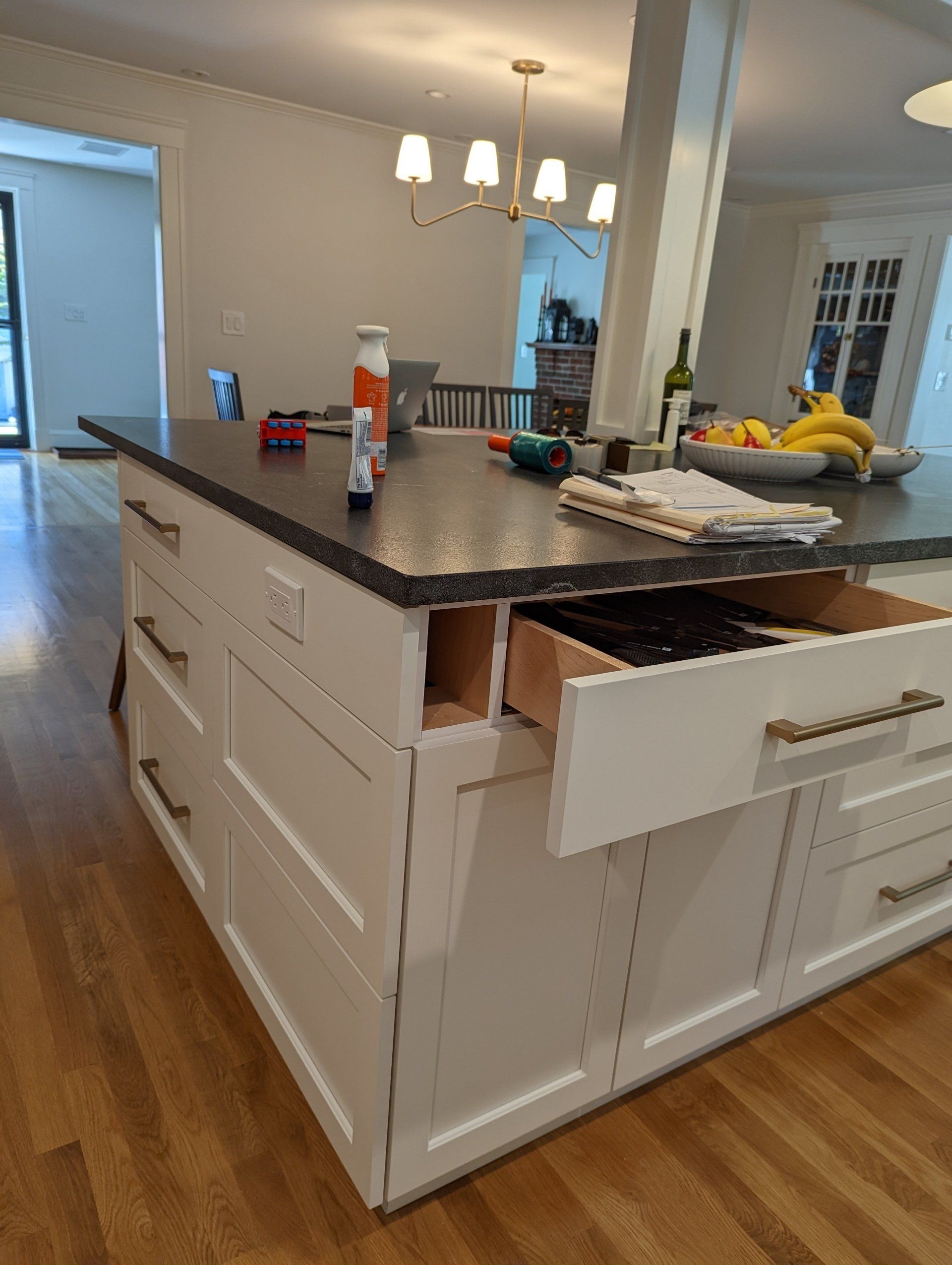 A kitchen island with drawers open and a bowl of bananas on the counter.