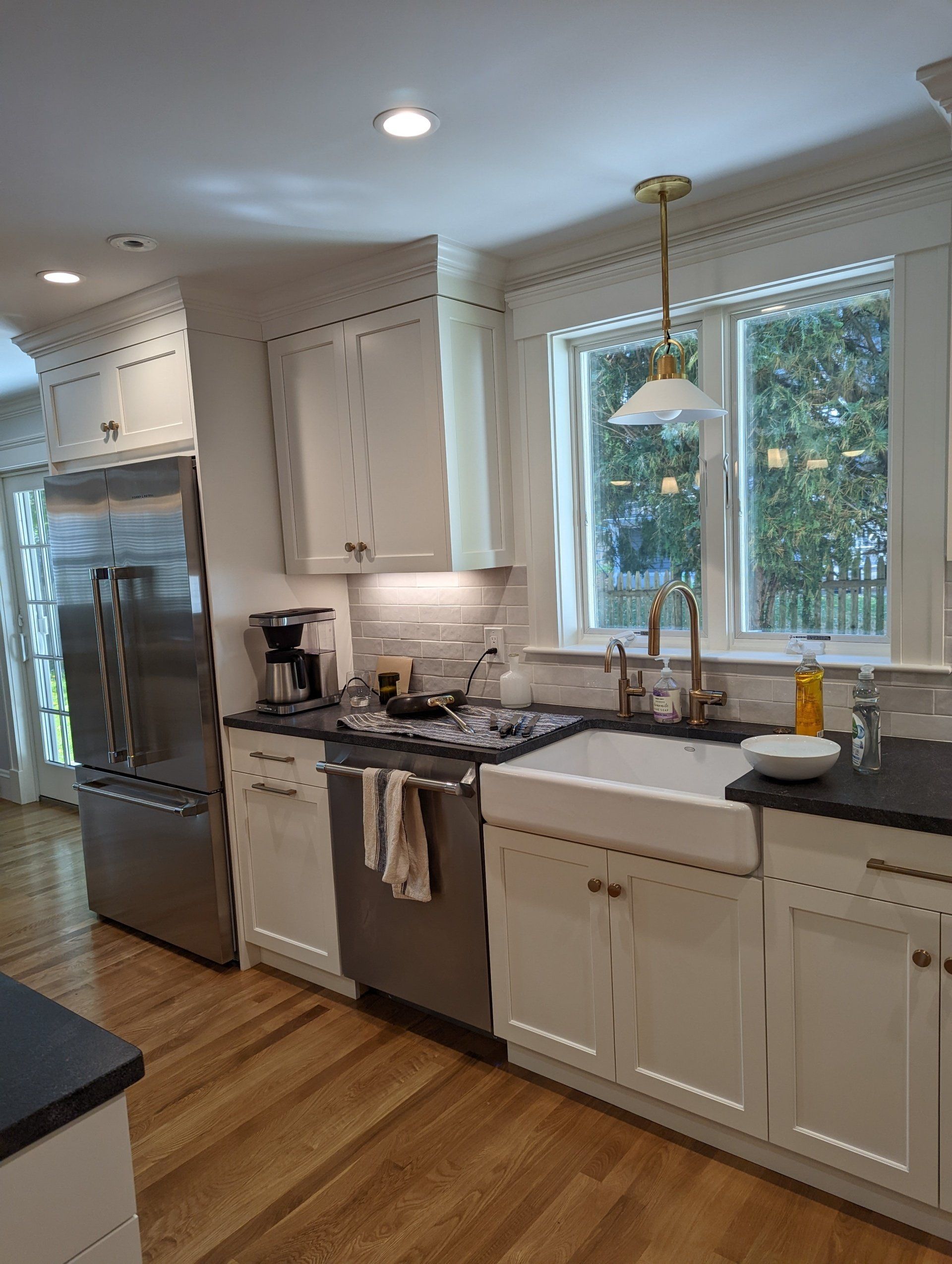 A kitchen with white cabinets , stainless steel appliances , a sink and a refrigerator.