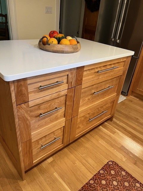 A kitchen island with a bowl of fruit on top of it.