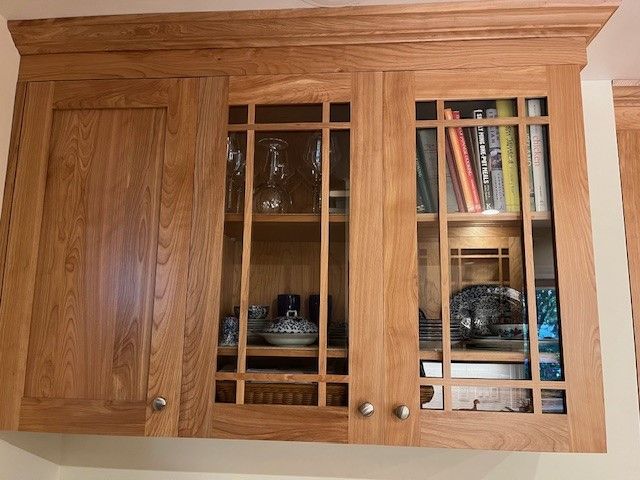 A wooden cabinet with glass doors and a shelf with books on it